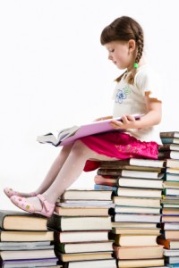 Girl sitting on many books reading contently